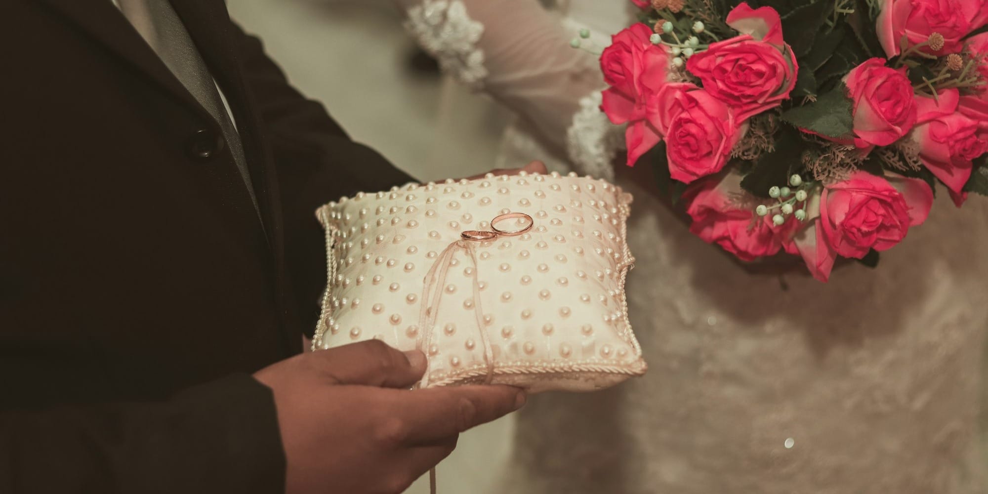 person holding white and pink floral textile